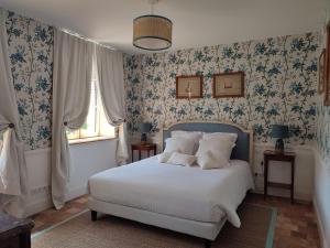Daubeuf-ServilleManoir de Daubeuf的一间卧室配有一张蓝色花卉壁纸床