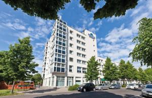 莱比锡acora Leipzig Living the City - Apartments的白色的建筑,有汽车停在停车场