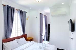 贡布Kampot Coco Guest House的一间卧室配有一张带蓝色窗帘的床和电视。