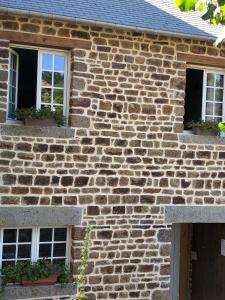 Ménil-Hubert-sur-Orne"La chambre des TISSERANDS"的砖屋,设有两扇窗户和一扇门