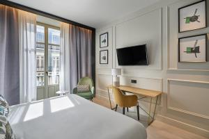 马拉加Vincci Larios Diez的酒店客房设有一张床、一张书桌和一台电视机。