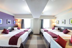 千岁千岁菲诺贝斯特韦斯特优质酒店的紫色墙壁的房间的一排床位