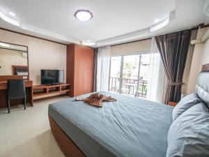 南芭堤雅Shiba Guesthouse的一间卧室设有一张床、一台电视和一个窗口。