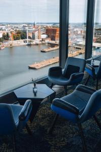 赫尔辛基赫尔辛基克拉丽奥酒店的一间带椅子和桌子的房间以及大窗户