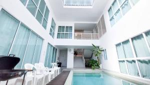 芭堤雅市中心The Inn10 Pool Villa Pattaya, Entire Villa, 9 Bedrooms, Private Indoor Swimming Pool, ดิ อินน์เท็น的一座带白色椅子的室内泳池