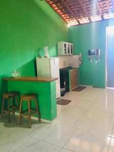 巴雷里尼亚斯Rosana House Bem estar em Barreirinhas Ideal para 5 pessoas的厨房设有绿色的墙壁、柜台和凳子