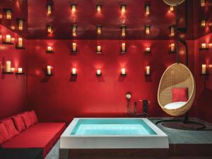 巴黎Chouchou Hotel的一个带红色墙壁和蜡烛的房间内的热水浴缸