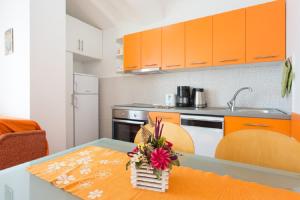 万塔西西Valentina Apartment and Studio的厨房配有橙色橱柜和鲜花桌