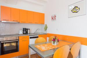 万塔西西Valentina Apartment and Studio的厨房配有橙色橱柜和桌椅