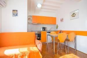 万塔西西Valentina Apartment and Studio的厨房配有橙色沙发和桌椅