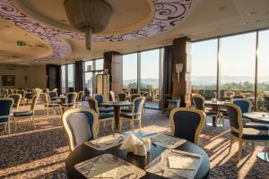 萨拉热窝马拉克丽景湾酒店的餐厅设有桌椅和大窗户。