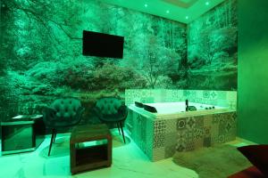 埃博利Alcova Suite&Relax的带浴缸和两把椅子的浴室以及电视。