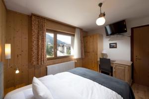 圣吕克乐美地酒店的一间卧室配有一张床、一张书桌和一个窗户。