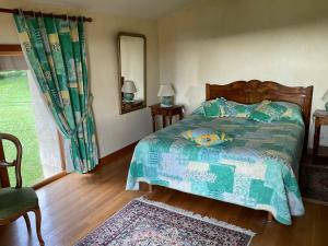 FuteauA l oree du bois的一间卧室配有一张带绿色棉被的床