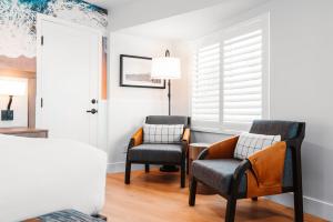 圣地亚哥Del Mar Beach Hotel的白色墙壁的房间设有两把椅子和一盏灯