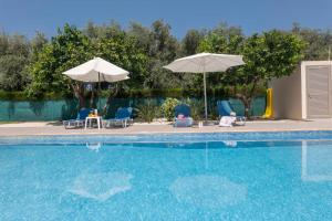 阿尔加卡Rafaella Beach Villa- Pvt Pool-Near Sea/Beach的游泳池配有两把遮阳伞和椅子以及桌椅