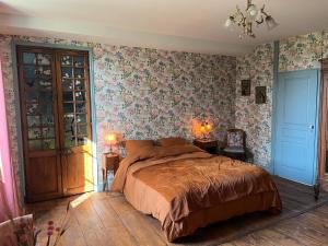 蒙蒂尼亚克Le Clos Chalmon Chambre d'hôte的一间卧室配有一张大床和花卉壁纸