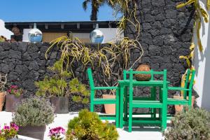 马赫5 Suites Lanzarote的两把绿色椅子坐在石墙旁边