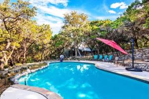 圣安东尼奥Salt Water Pool & Backyard Oasis @ Wild Eagle的一个带红色遮阳伞和椅子的游泳池