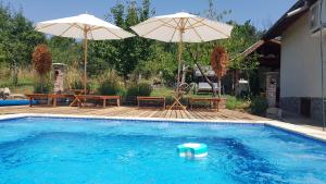 丘斯滕迪尔Къща за гости Каза Роза - Swiss Style Chalet Casa Rosa Guest House的游泳池配有两把遮阳伞、一张桌子和长椅