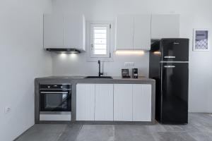 阿波罗尼亚Manesis Suites的厨房配有白色橱柜和黑色冰箱。