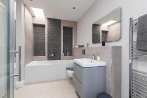 吉伦Caddyshacks Gullane, 4 bedroom, 4 bath, Golf, Beach的浴室配有卫生间、浴缸和水槽。