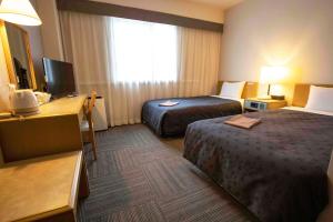 水户美图庭院酒店的酒店客房设有两张床、一张桌子和一台电视。