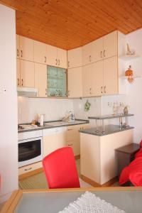 尼亚卢卡Apartments with a parking space Vela Luka, Korcula - 7551的厨房配有白色橱柜和红色椅子