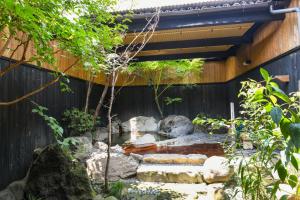 植木町Ryokan Yayanoyu的围栏前有岩石和池塘的花园