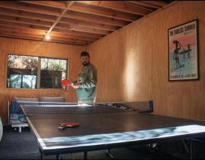 哈海Ponga eco-lodge的站在一个配有乒乓球桌的房间的人