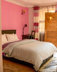 姆万扎Samanene Hotel的一间卧室配有一张床和粉红色的墙壁