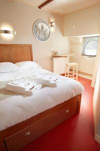 瓦兹河畔欧韦Péniche Daphné's的一间卧室配有一张带白色床单的大床