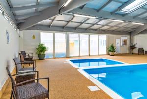 托波因特Finest Retreats - Serendipity Lodge的一个带椅子的泳池间和游泳池