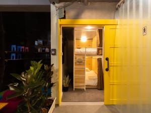 曼谷Khao San Social Capsule Hostel的黄色的门通向一间带双层床的卧室