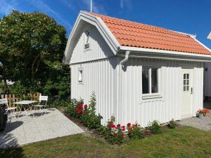 卡尔马Attefallshus på Ängö i Kalmar的一座白色的小建筑,有红色的屋顶