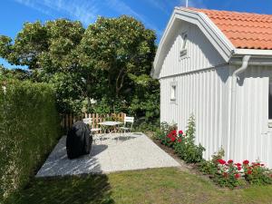 卡尔马Attefallshus på Ängö i Kalmar的一座白色的小建筑,旁边设有桌椅