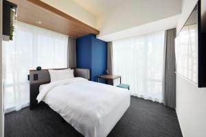 东京Prince Smart Inn Ebisu的卧室配有白色的床和蓝色的墙壁