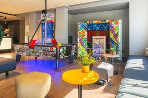美因河畔法兰克福法兰克福加鲁斯维亚特尔A&O经济型连锁酒店 的一间设有色彩缤纷家具的客房和一间带桌子的客房