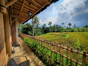 里辛RUMAH @ Sawah Ijen的一个带桌椅的门廊和稻田