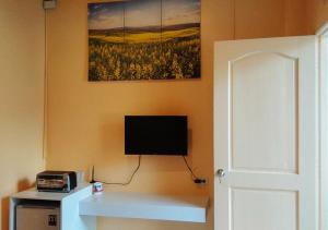OraconRedDoorz @ Southern Suites Guimaras的一间配有电视的房间和一张画面的墙壁