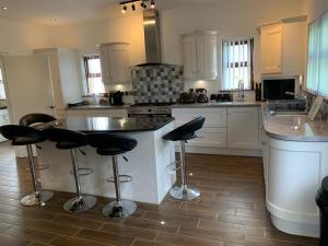 Dromore3 bedroom detached bungalow的厨房配有白色橱柜和带凳子的台面