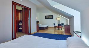波尔尼克Le Mauritia Hotel et Spa的一间带白色床的卧室和一间带桌子的房间