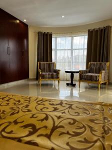 姆巴巴内Open House Hotel的一间设有两把椅子、一张桌子和地毯的房间