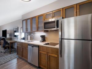 苏城Staybridge Suites - Sioux City Southeast, an IHG Hotel的厨房配有不锈钢冰箱和木制橱柜