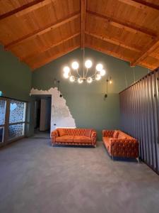 GîrbovaPensiunea Casa Buna的两个橙色的沙发,位于一个配有吊灯的房间