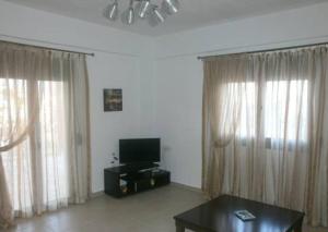 卡米拉日基帕里西度假屋的客厅配有窗帘、电视和桌子