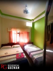 亚奎巴Residencial Guzmán 1的绿墙客房内的两张床