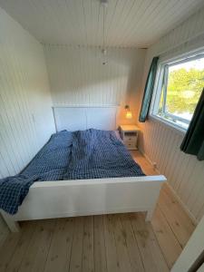 VeksøHyggelig sommerhus. med udsigt, til vand fra senge的一个小房间的一个床位,设有窗户