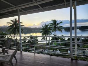 苏瓦Suva Hideaway Villa的享有水景和棕榈树景致的门廊