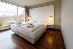 不莱梅赛马场大西洋饭店的一间卧室设有两张床和大窗户